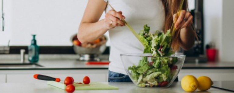 Frau bereitet einen gesunden Salat für Fitnessernährung zu.