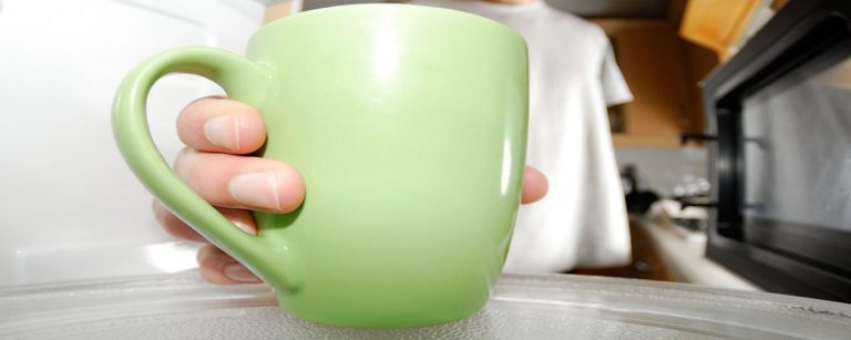 Grüne Tasse im Mikrowellen-Check für Fitness-Mahlzeiten.