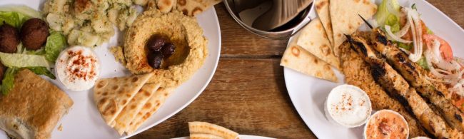 Gesundes mediterranes Gericht: Hummus, Falafel, gegrillte Hähnchenspieße mit Reis und Salat.