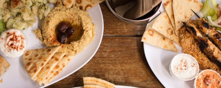 Gesundes mediterranes Gericht: Hummus, Falafel, gegrillte Hähnchenspieße mit Reis und Salat.