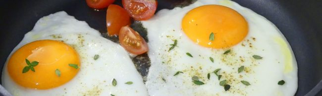 Zwei Spiegeleier mit Tomaten, verfeinert mit Kräutern, perfekt für Ihr Fitness-Frühstück.