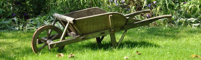 Holz-Schubkarre mit einem Rad auf grünem Rasen im Garten, ideal für Outdoor-Fitness.