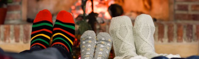 Gemütliche Füße in Stricksocken am Kaminfeuer, perfekt für die Erholung nach dem Training.
