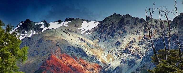 Berglandschaft mit Schnee, rotem Gestein und Bäumen. Ideal für Outdoor-Fitness-Ernährung.