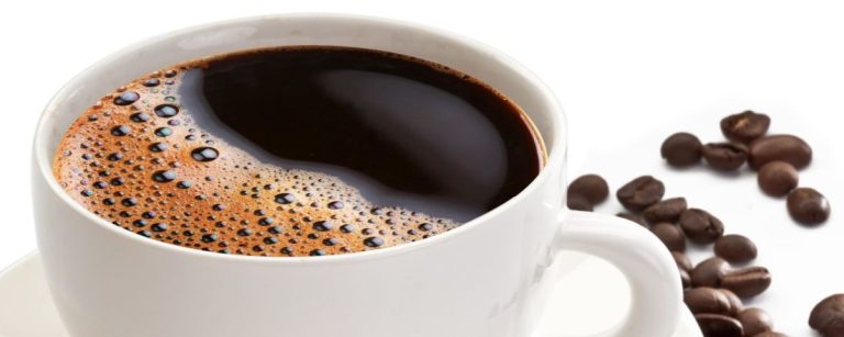 Eine Tasse Kaffee mit Schaum und Kaffeebohnen, perfekt für dein Fitness-Ernährungsprogramm.