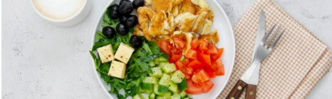 Fitness-Frühstück: Rührei, Salat, Tomaten, Gurke, Käse und Oliven. Gesunde Mahlzeit.