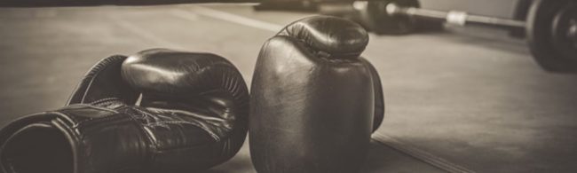 Schwarze Boxhandschuhe liegen auf einem Boxring.