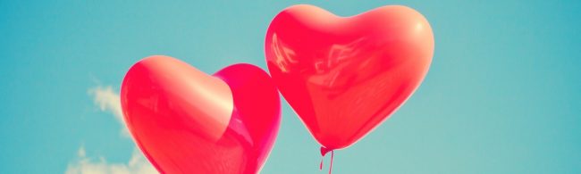 Zwei rote Herzballons vor blauem Himmel – Symbol für Liebe und gesunden Lebensstil.