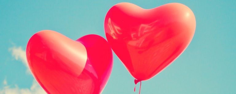 Zwei rote Herzballons vor blauem Himmel – Symbol für Liebe und gesunden Lebensstil.