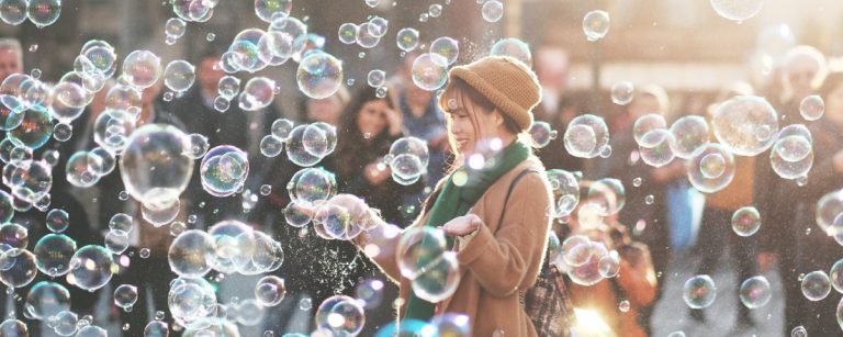 Frau lacht in Seifenblasen, eine fröhliche Erinnerung an gesunde Ernährung und Fitness für ein lebendiges Leben.