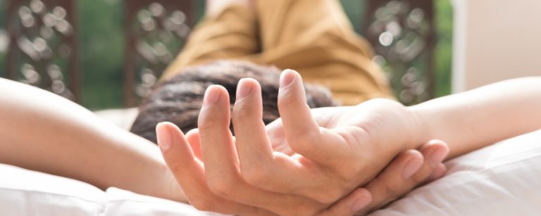 Entspannter Mensch mit Händen hinter dem Kopf auf weißem Kissen, ein Symbol für Erholung nach dem Training.