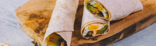 Frühstücks-Burrito mit Ei, Avocado und Speck für einen energiegeladenen Start.