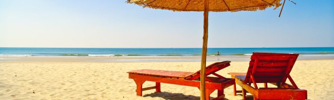 Rote Liegen am Strand unter Sonnenschirm, gesunde Erholung für dein Training.