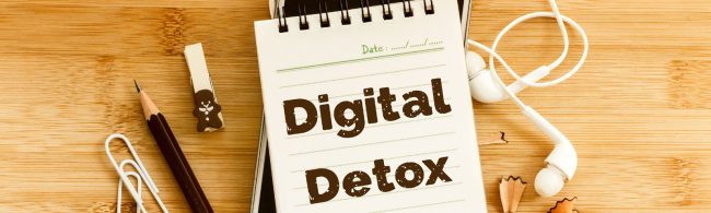 Schreibtisch-Layout für digitale Entgiftung mit Notizbuch, Stift, Kopfhörern und Büroklammern.