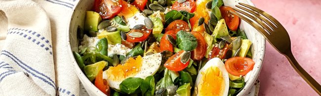 Gesunder Fitness-Salat mit Ei, Avocado, Tomaten und Kernen.