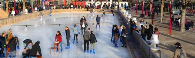 Ice skater gliding in low stance on an outdoor winter rink, showing strong leg drive and stable core with frosty breath in the air.