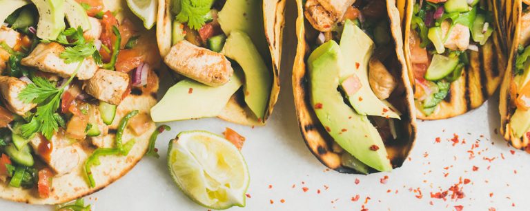 Whole-wheat tortilla next to a bright beetroot veggie wrap on a wooden board, surrounded by fresh salad ingredients.