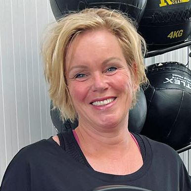 Frau lächelt, steht vor Trainingsgeräten, Fitnessernährung.