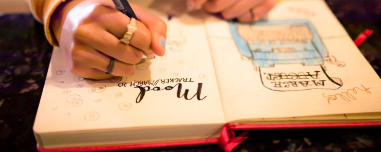 Close-up of a beautiful bullet journal spread with colorful markers, neatly organized index and symbol keys on a clean desk.