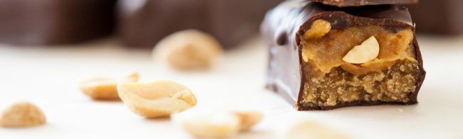 Close-up of homemade healthy Snickers bars with date caramel, peanuts and dark chocolate coating