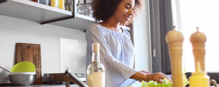 Frau bereitet gesunde Mahlzeit mit frischem Salat zu, ideal für Fitness-Ernährung.