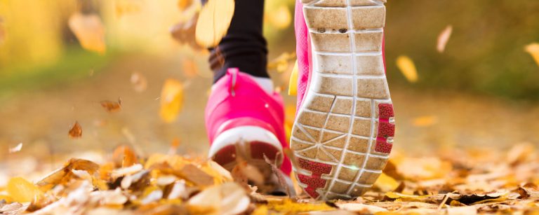 Person walking outdoors with fitness tracker showing daily step goal of 10,000