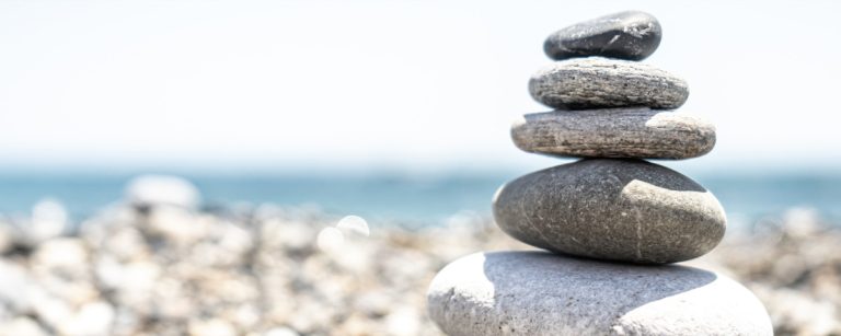 Balancierte Steine am Strand symbolisieren Gleichgewicht und Ruhe. Fitness, gesunde Ernährung und Wohlbefinden mit BenFit.