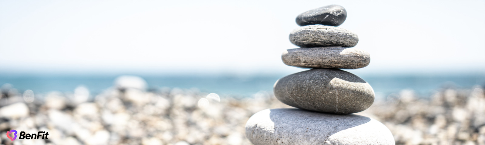 Balancierte Steine am Strand symbolisieren Gleichgewicht und Ruhe. Fitness, gesunde Ernährung und Wohlbefinden mit BenFit.