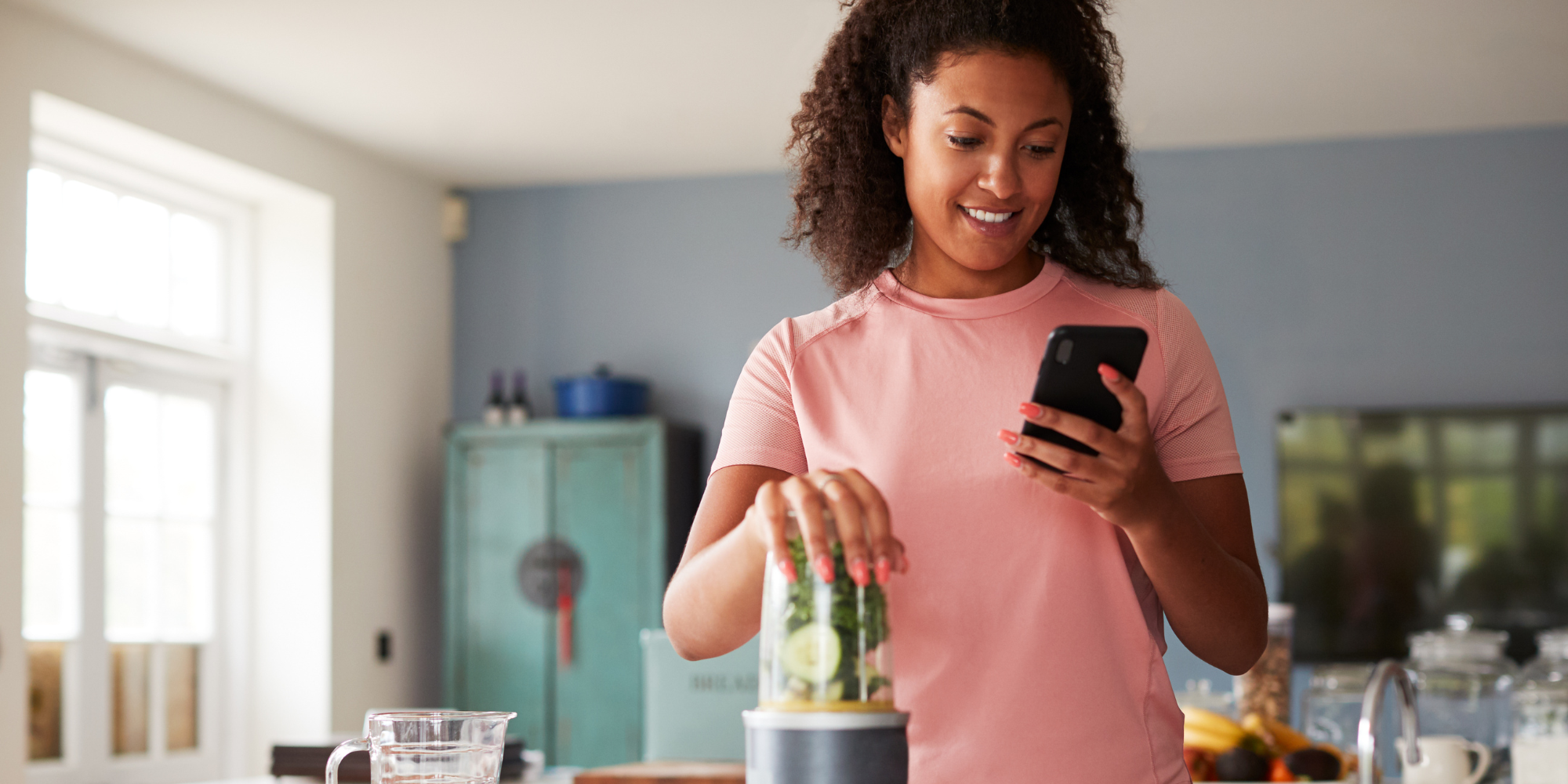 Woman tracking her food while making a smoothie in the kitchen Woman tracking her food while making a smoothie in the kitchen