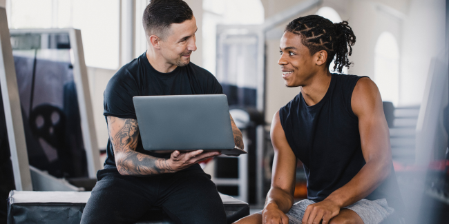 personal trainer met laptop die iets aan klant laat zien