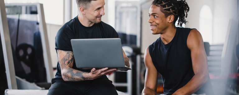 personal trainer met laptop die iets aan klant laat zien