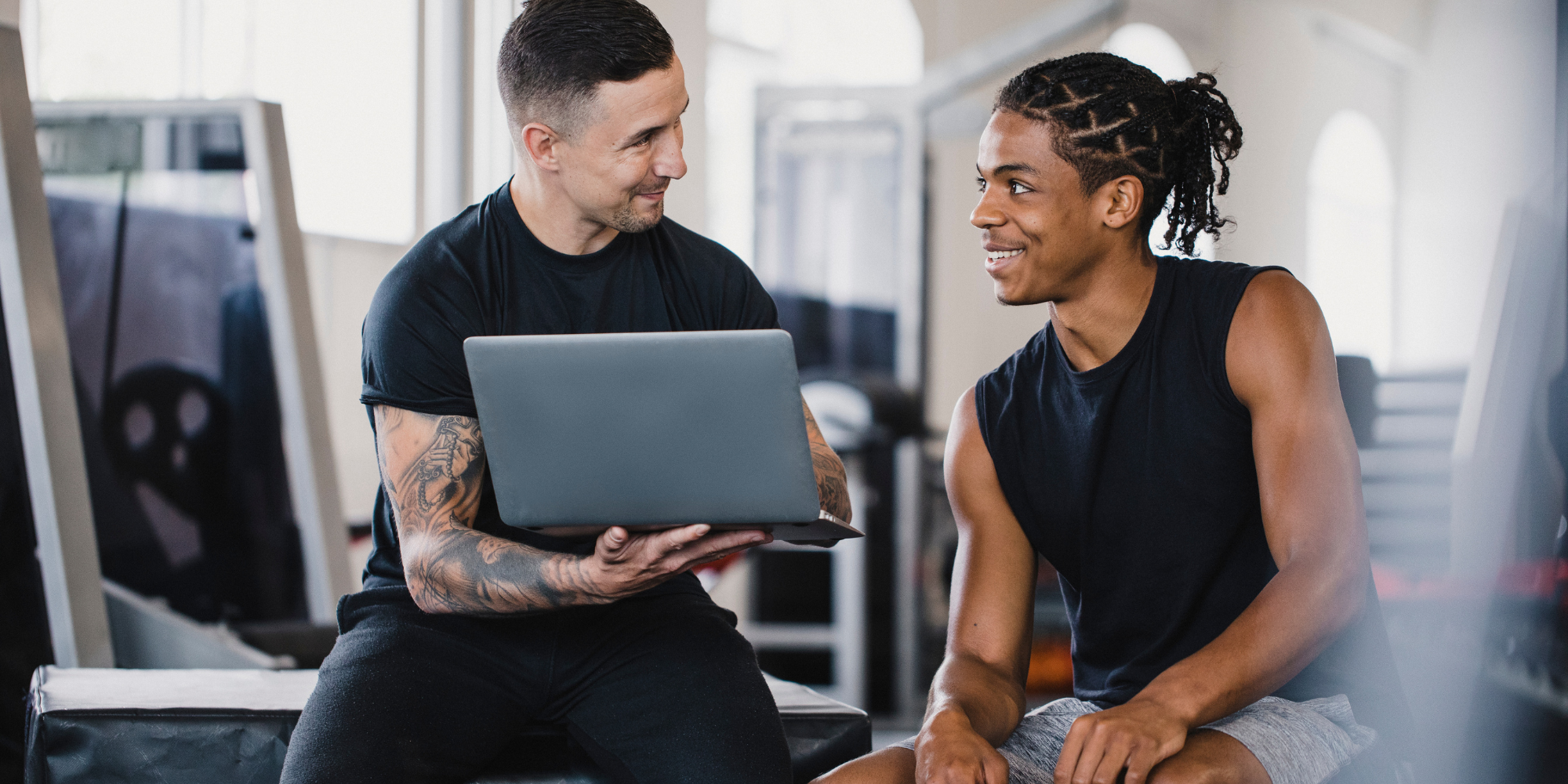 personal trainer met laptop die iets aan klant laat zien